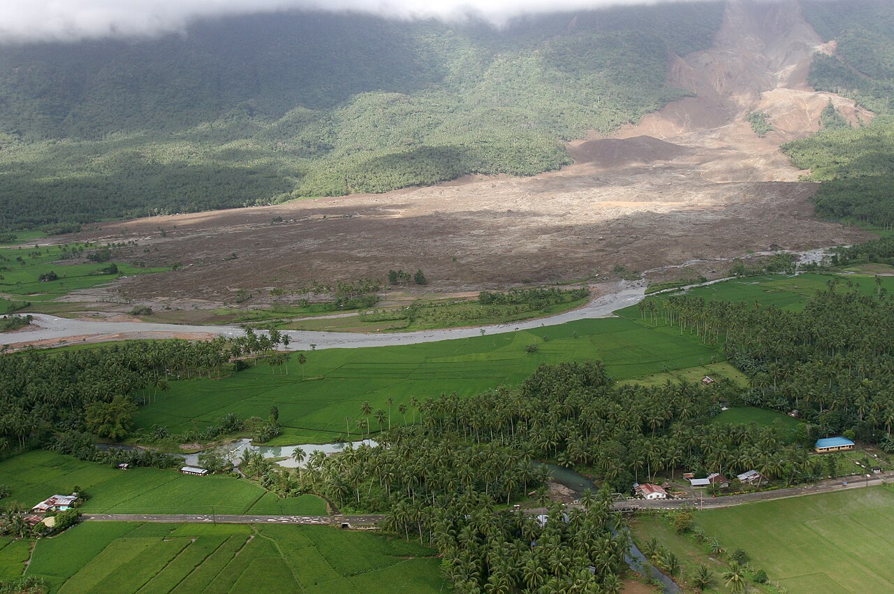 Archive aerial photo from Southern Leyte: the 2006 Guinsaugon landslide scar stretches across fields below the mountain.